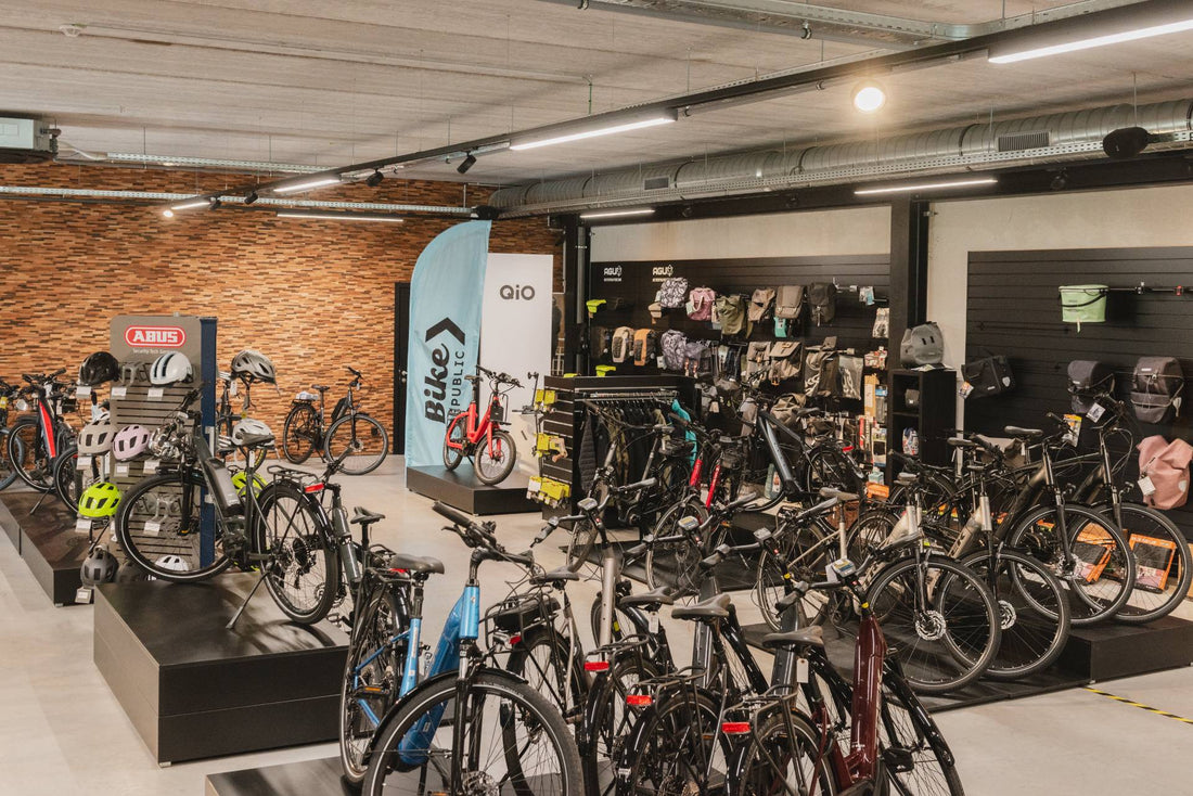 Interior of a Bike Republic store displaying e-bikes, bike bags, helmets, and other accessories, with a distinctive brick-style wall and spacious showroom layout.