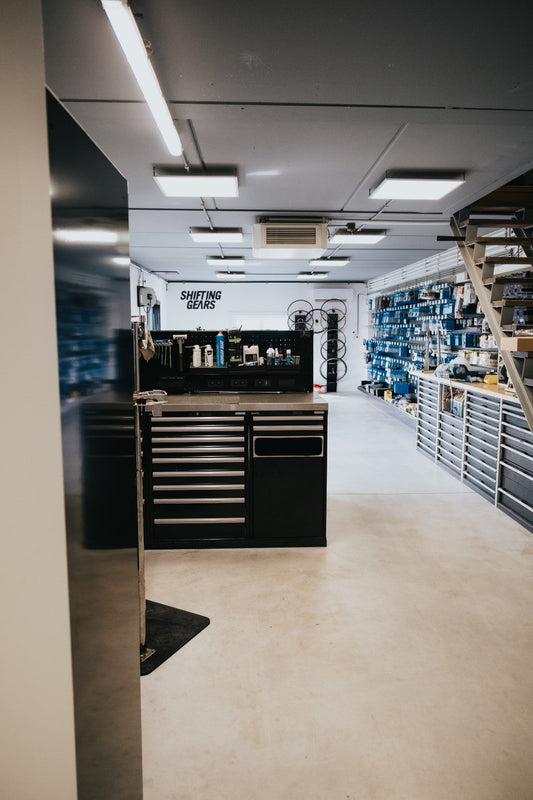 Interior of the Specialized Brugge workshop with tool cabinets, workbenches, and spare parts organized on the walls.