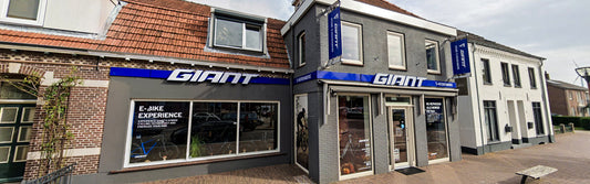 Front view of the bicycle shop with the Giant logo and large windows displaying bikes and posters.